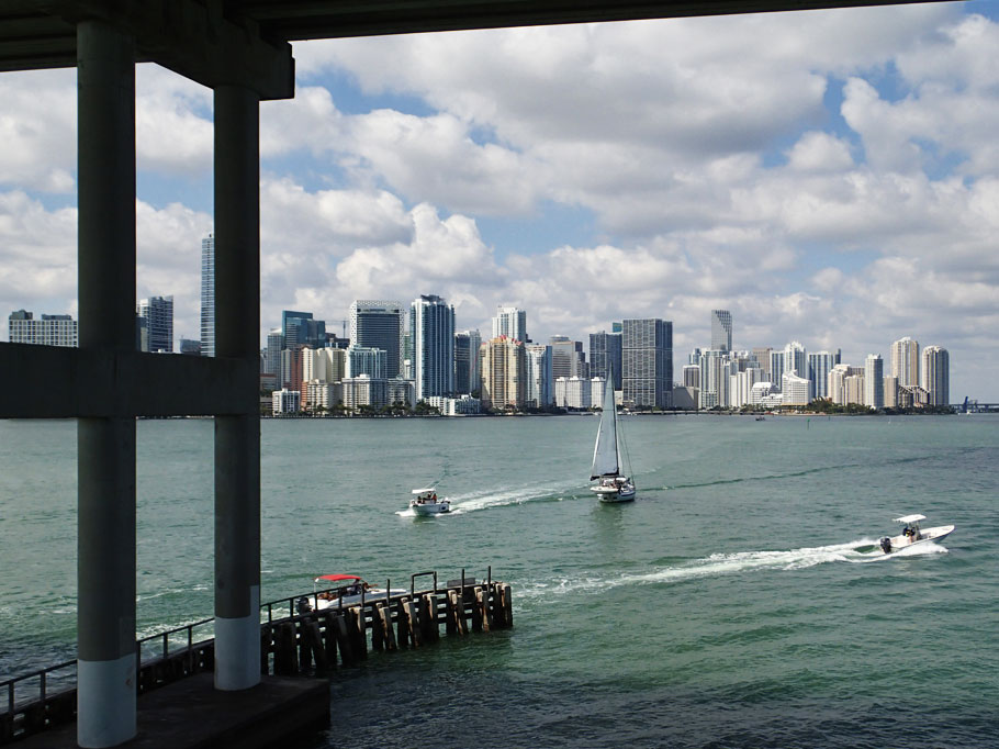 Sailboat sails under the bridge and into the channel in Miami.